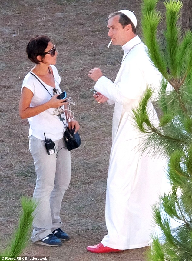 Holy smokes! Jude Law cut an unusual figure as he puffed away on a cigarette while still wearing his papal robes, skullcap and collar in-between filming scenes for The Young Pope in Rome on Tuesday