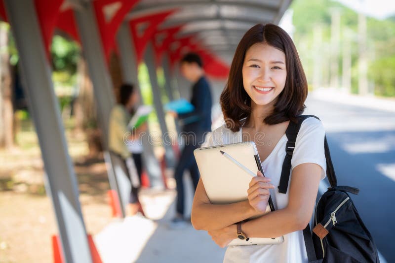 Asian student girl stand with group of happy teen high school students. Outdoors royalty free stock photo