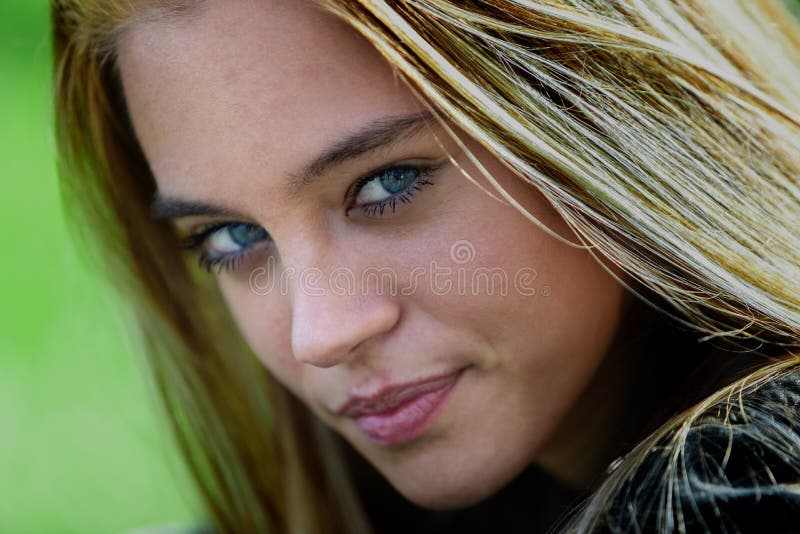 Close up portrait of pretty young blue eyed woman. Close up cropped head shot portrait of pretty young blue eyed woman with long blond hair turning to give the royalty free stock photo