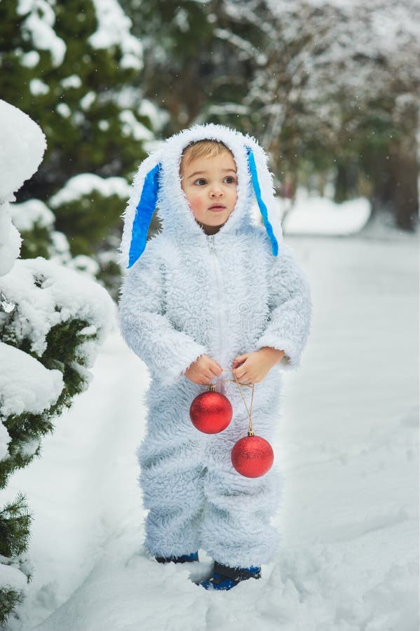 A little boy dressed as rabbit meets new year. Portraita little boy dressed as rabbit in winter forest. Child with christmas balls. Snowy park. character xmas stock photo