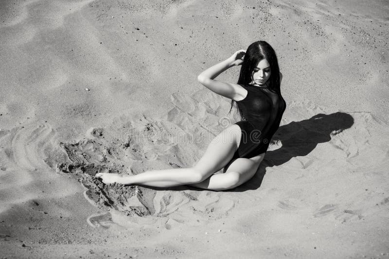 woman or girl in seductive body suit lying on the sand stock images