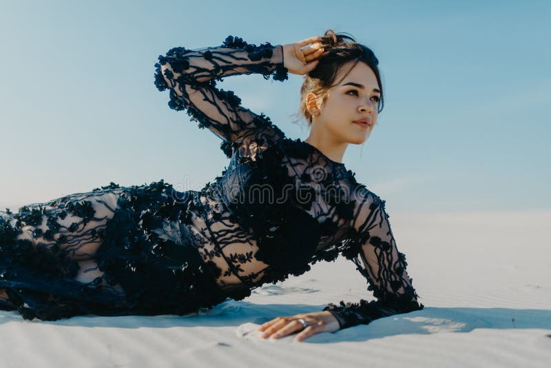Woman lies and poses in desert on white sand stock photography